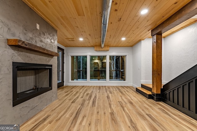 unfurnished living room featuring light hardwood / wood-style flooring, wooden ceiling, and a fireplace