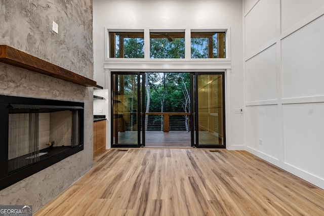 unfurnished living room featuring light wood-type flooring and a high ceiling