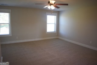 empty room with ceiling fan and carpet