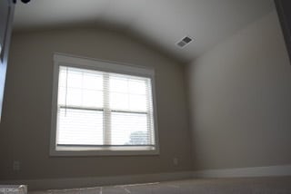 unfurnished room featuring lofted ceiling