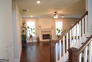 interior space with a fireplace, brick wall, ceiling fan, and dark hardwood / wood-style floors