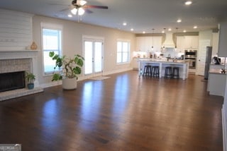 living room featuring a brick fireplace, brick wall, ceiling fan, and dark hardwood / wood-style floors