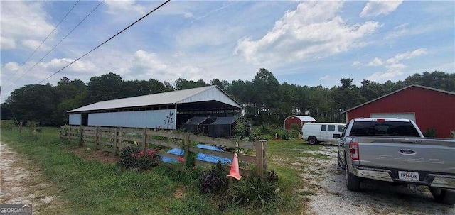 view of yard with fence, a detached garage, and an outdoor structure