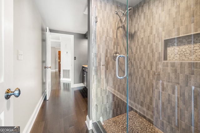 bathroom with a shower with shower door, hardwood / wood-style flooring, and vanity