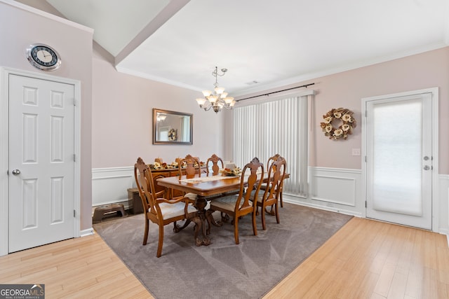 dining area featuring an inviting chandelier, ornamental molding, vaulted ceiling, and hardwood / wood-style floors