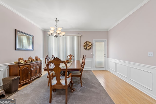 dining space with ornamental molding, light hardwood / wood-style flooring, and a notable chandelier