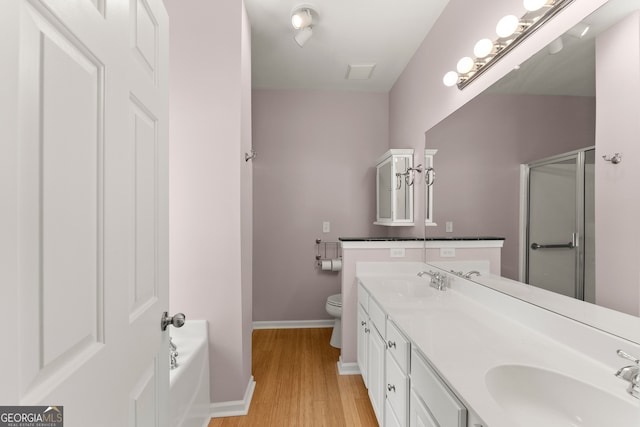 full bathroom with shower with separate bathtub, hardwood / wood-style flooring, vanity, and toilet