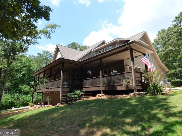 back of property featuring a wooden deck and a lawn