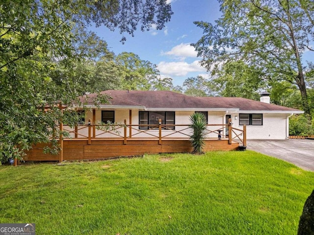 exterior space featuring driveway, brick siding, a lawn, and a chimney