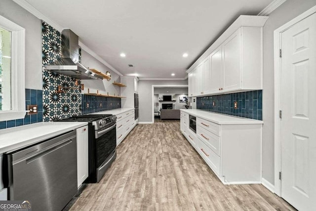 kitchen with tasteful backsplash, light hardwood / wood-style flooring, appliances with stainless steel finishes, white cabinets, and wall chimney range hood