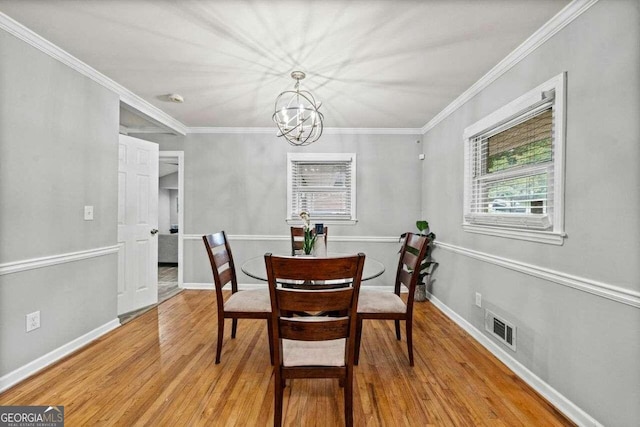 dining space featuring ornamental molding, an inviting chandelier, and light hardwood / wood-style floors