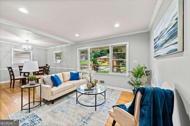 living room featuring a chandelier, crown molding, and light hardwood / wood-style flooring