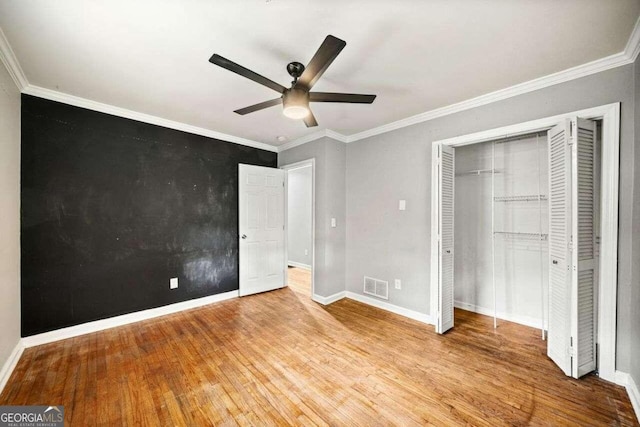 unfurnished bedroom featuring crown molding, ceiling fan, a closet, and hardwood / wood-style flooring