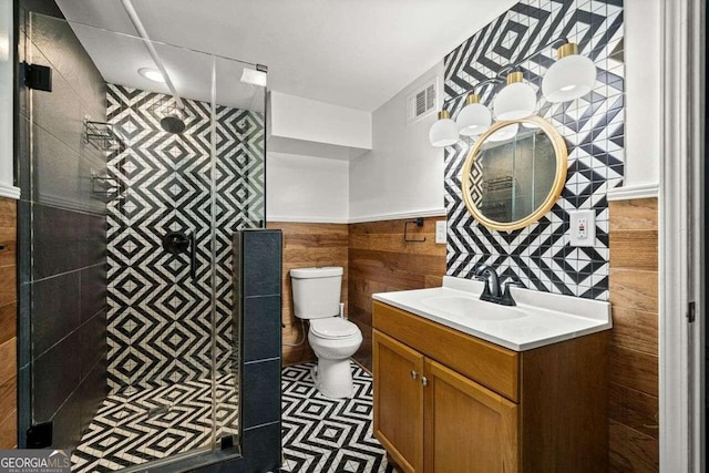 bathroom with vanity, toilet, and tile walls