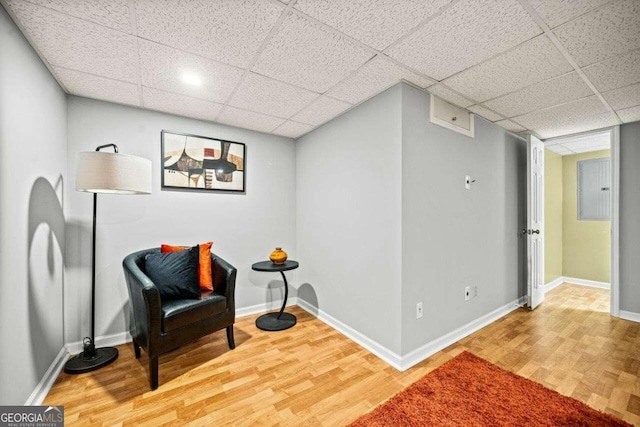 sitting room featuring hardwood / wood-style flooring, electric panel, and a drop ceiling