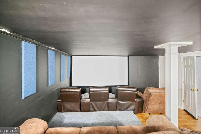 cinema room featuring light wood-type flooring and decorative columns