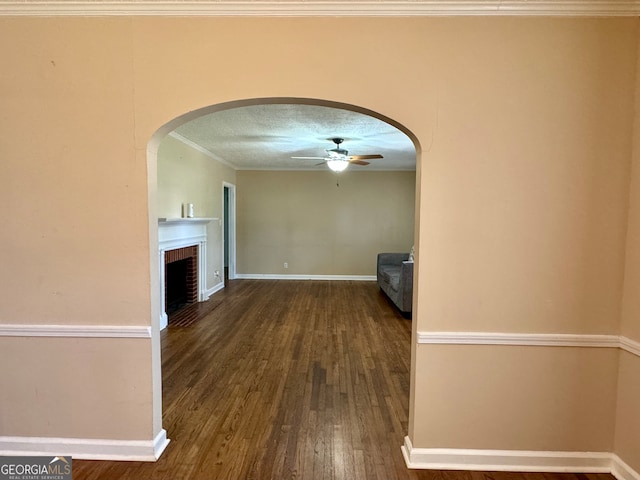 interior space featuring a fireplace, hardwood / wood-style floors, crown molding, a textured ceiling, and ceiling fan