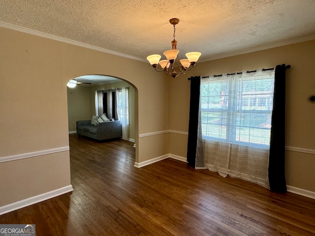 empty room with an inviting chandelier, dark hardwood / wood-style flooring, ornamental molding, and a textured ceiling