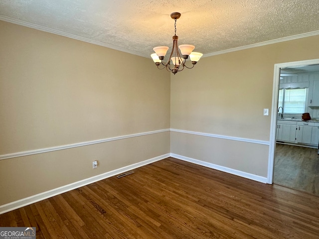 spare room with dark hardwood / wood-style floors, crown molding, a notable chandelier, and a textured ceiling