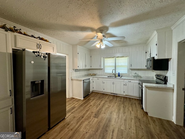 kitchen with sink, hardwood / wood-style floors, appliances with stainless steel finishes, and white cabinetry