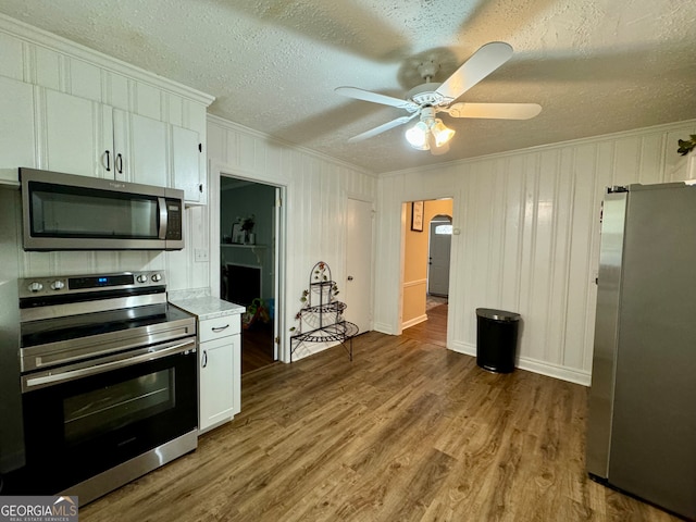 kitchen featuring white cabinets, appliances with stainless steel finishes, wood-type flooring, ceiling fan, and a textured ceiling