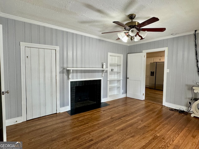 unfurnished living room with crown molding, a textured ceiling, a brick fireplace, ceiling fan, and hardwood / wood-style flooring