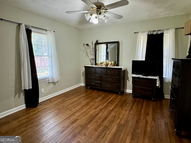 bedroom with a textured ceiling, dark wood-type flooring, and ceiling fan