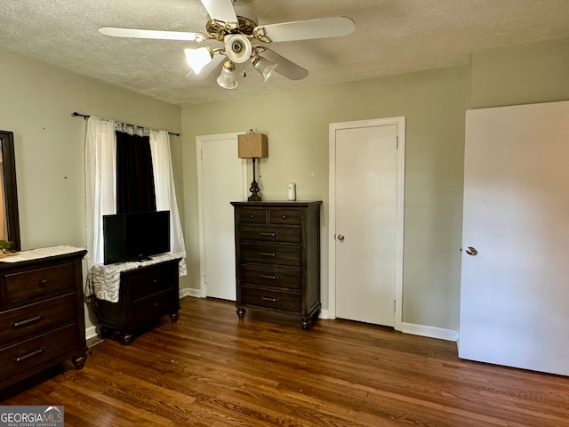 bedroom featuring ceiling fan, dark hardwood / wood-style flooring, and a textured ceiling