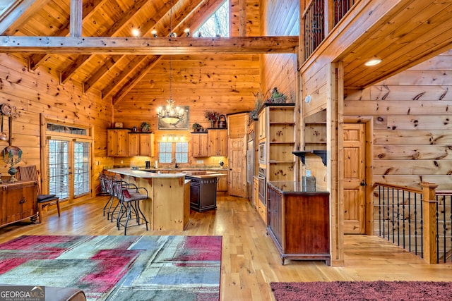 kitchen with decorative light fixtures, a kitchen breakfast bar, light wood-type flooring, and wood walls