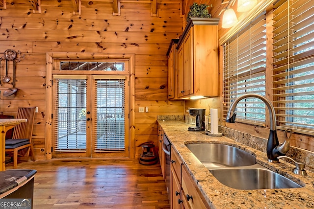 kitchen featuring french doors, sink, dishwasher, hardwood / wood-style flooring, and light stone countertops