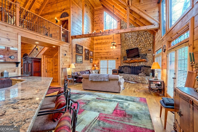 living room with a healthy amount of sunlight, wooden walls, and a stone fireplace