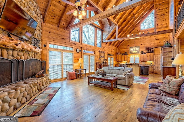 living room with a fireplace, light hardwood / wood-style floors, wooden ceiling, and wood walls