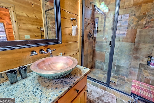 bathroom with walk in shower, vanity, and wood walls