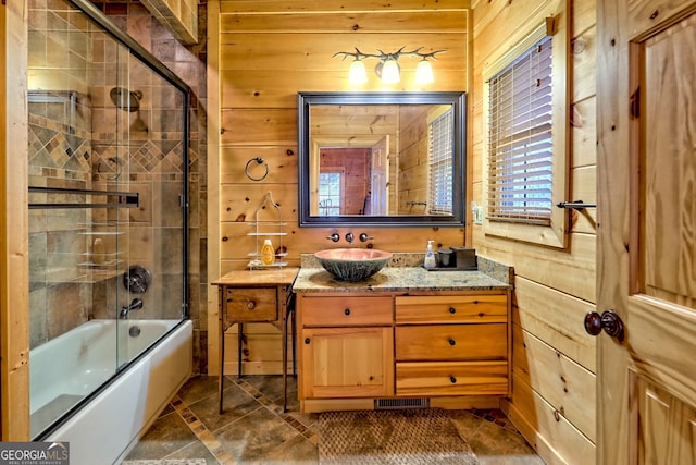 bathroom featuring vanity, wooden walls, and shower / bath combination with glass door