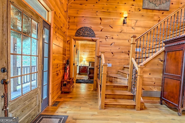 entryway featuring light wood-type flooring and wooden walls