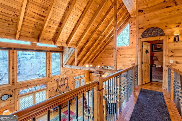 corridor with hardwood / wood-style floors, wooden walls, plenty of natural light, wooden ceiling, and beamed ceiling