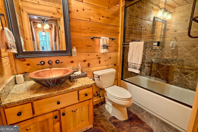 full bathroom with toilet, vanity, bath / shower combo with glass door, and wood walls