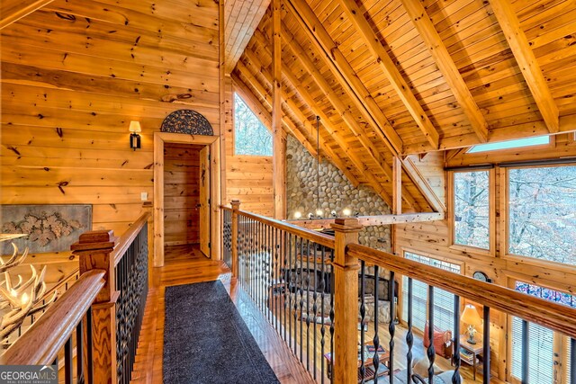 corridor with vaulted ceiling with beams, wooden ceiling, and wood walls