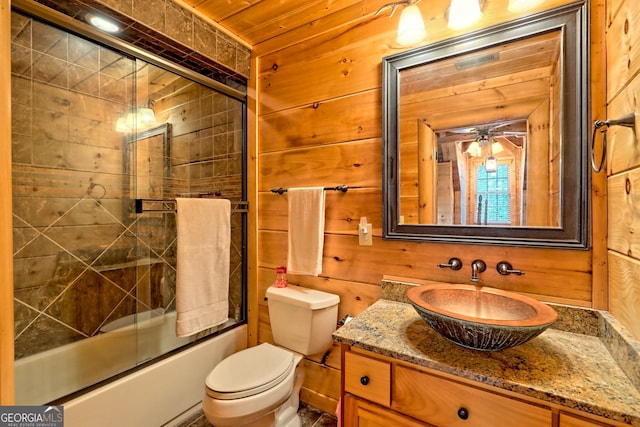 full bathroom with toilet, vanity, shower / bath combination with glass door, and wood walls