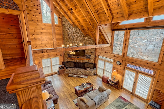 living room with beamed ceiling, wooden walls, high vaulted ceiling, and wooden ceiling