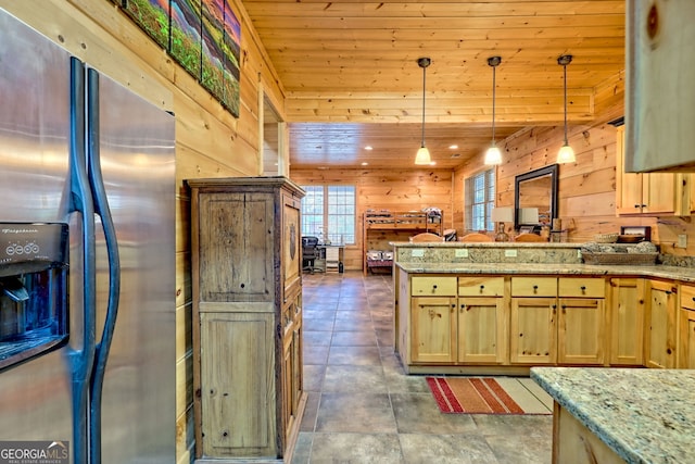 kitchen with wood walls, wood ceiling, stainless steel fridge, pendant lighting, and light stone countertops