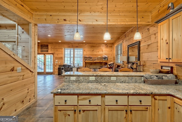 kitchen featuring wood walls, hanging light fixtures, wooden ceiling, dark tile patterned flooring, and light stone countertops