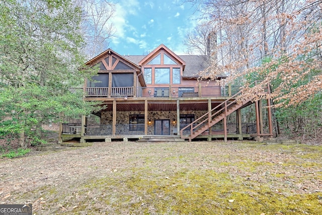 rear view of property with a wooden deck, a yard, and a sunroom