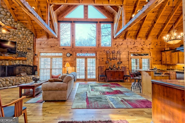 living room featuring light hardwood / wood-style flooring, a fireplace, wooden ceiling, french doors, and wood walls