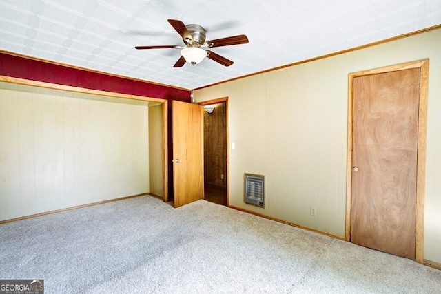 unfurnished bedroom with crown molding, heating unit, ceiling fan, and carpet