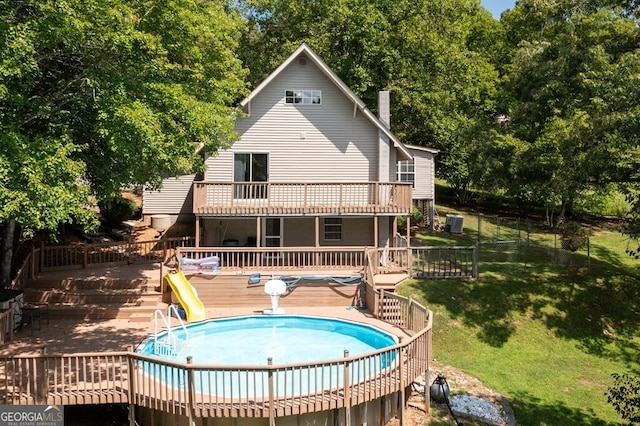 rear view of house with a pool side deck and a lawn