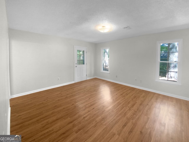 spare room with a textured ceiling and hardwood / wood-style floors