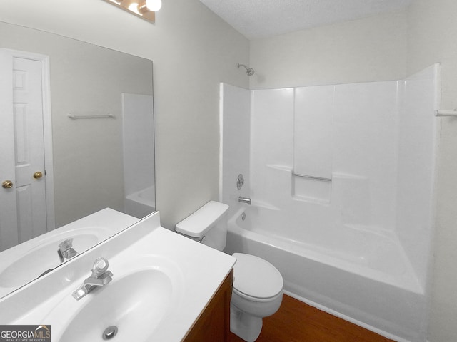 full bathroom with hardwood / wood-style flooring, a textured ceiling, toilet, shower / bathing tub combination, and vanity