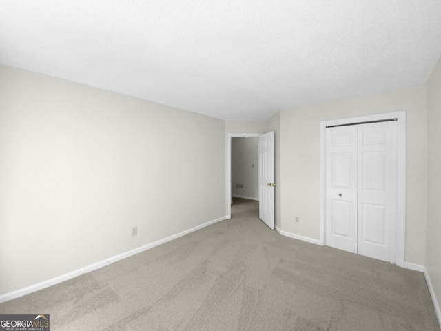 unfurnished bedroom with a closet and light colored carpet