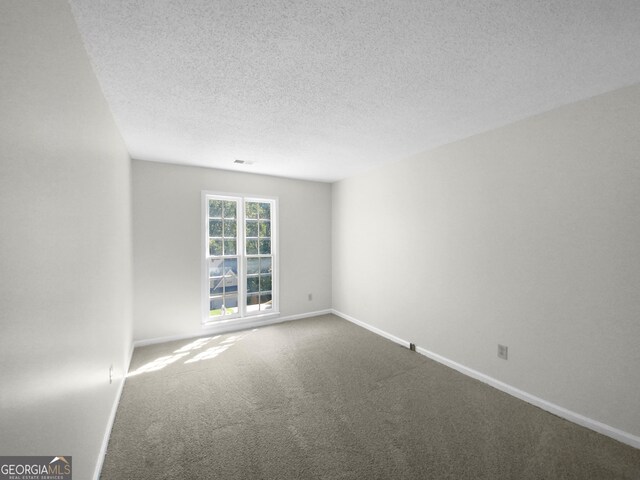 spare room with a textured ceiling and carpet floors